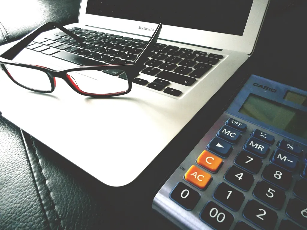 Portátil, gafas y calculadora para presupuestar una página web