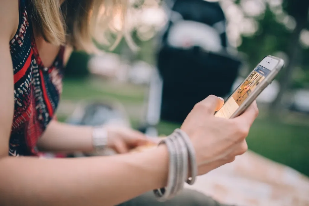 Mujer sonriente revisando sus redes sociales en el celular